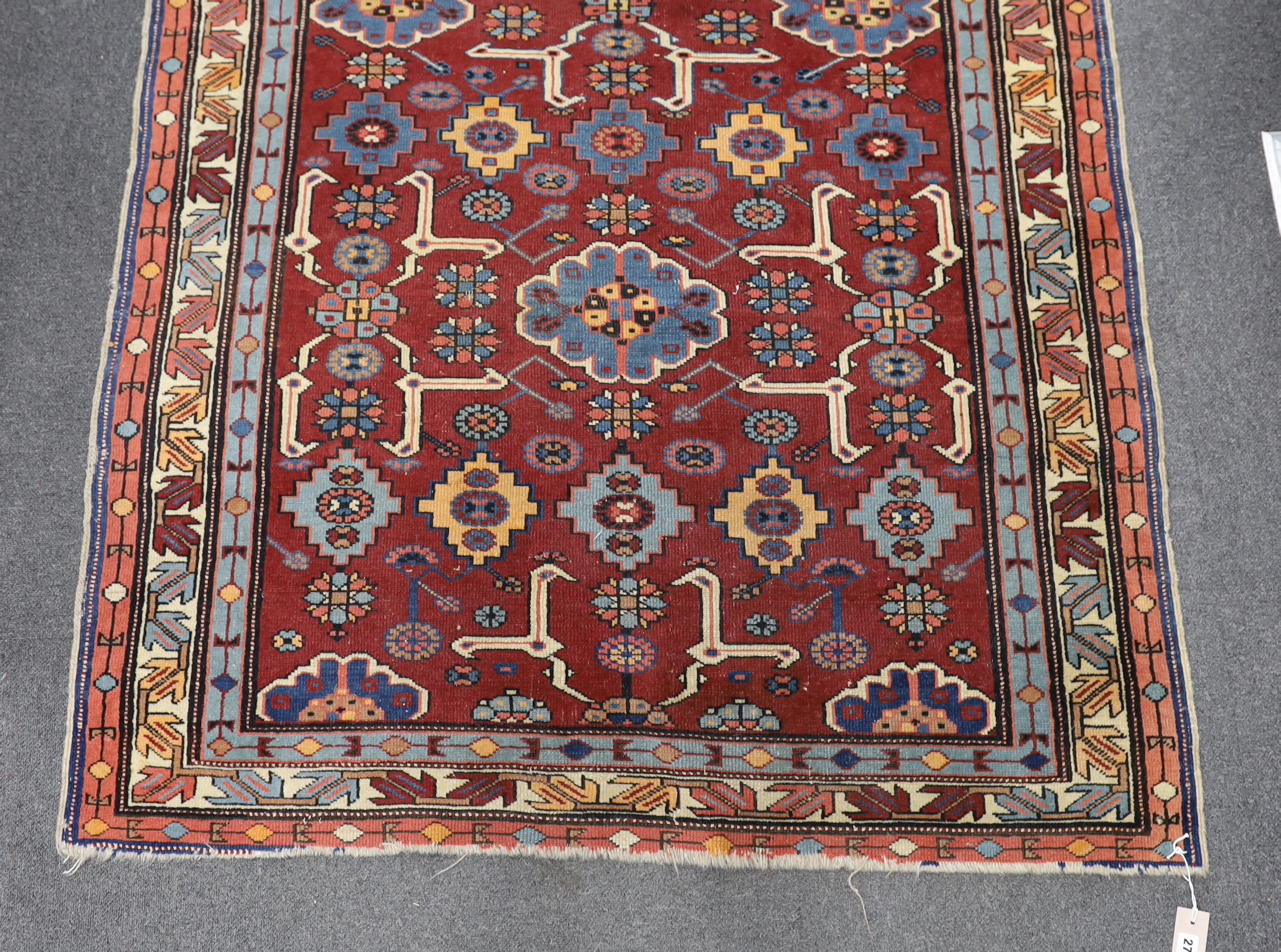 A Caucasian burgundy ground rug, 220 x 128cm